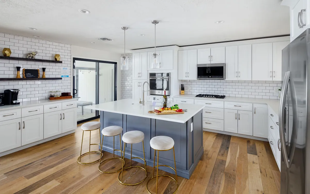 A modern kitchen with a central island countertop, bar stools, sleek cabinetry, and stainless steel appliances. The design is open and flows naturally into the living area, perfect for entertaining and keeping everyone connected.