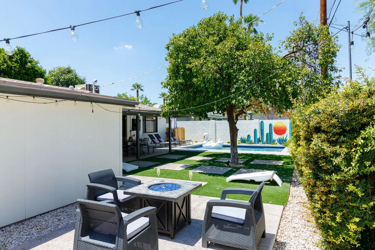 A cheerful outdoor space featuring a swimming pool, decorative mural, patio seating, and lush greenery. The arrangement is inviting for relaxation, informal meetings, or evening socializing in a tranquil yet lively setting.